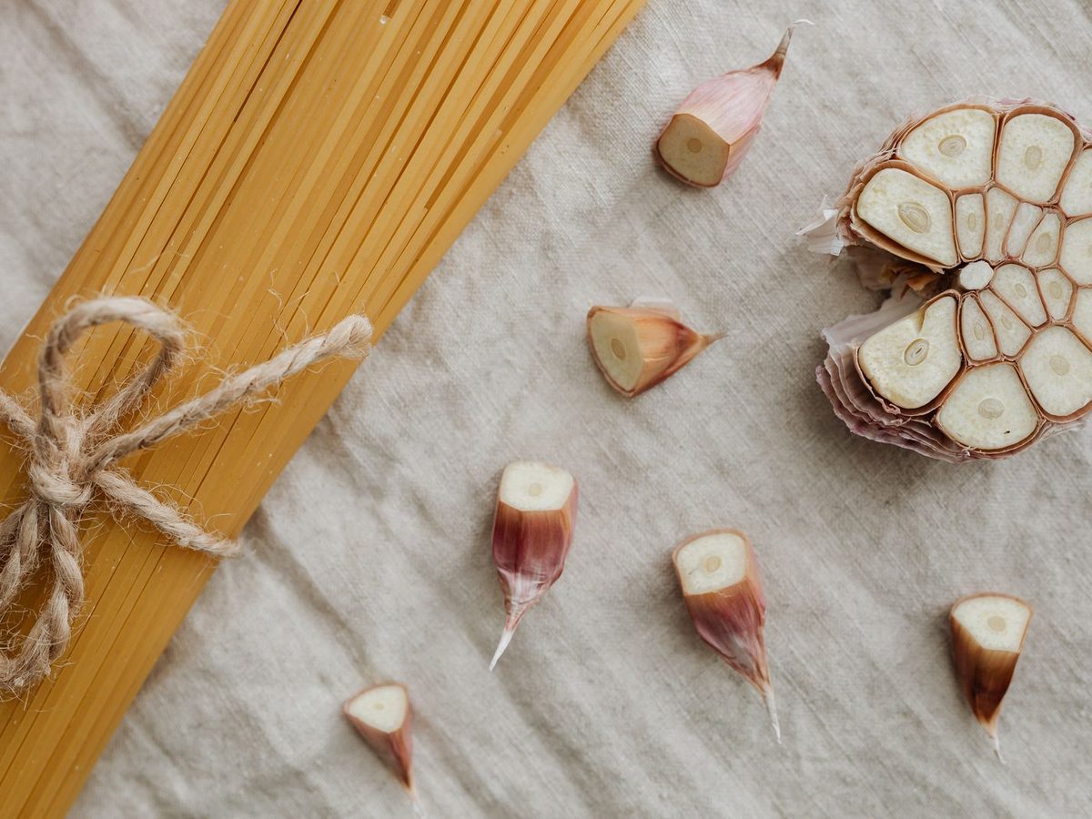 Dried spaghetti tied with twine and a halved garlic bulb