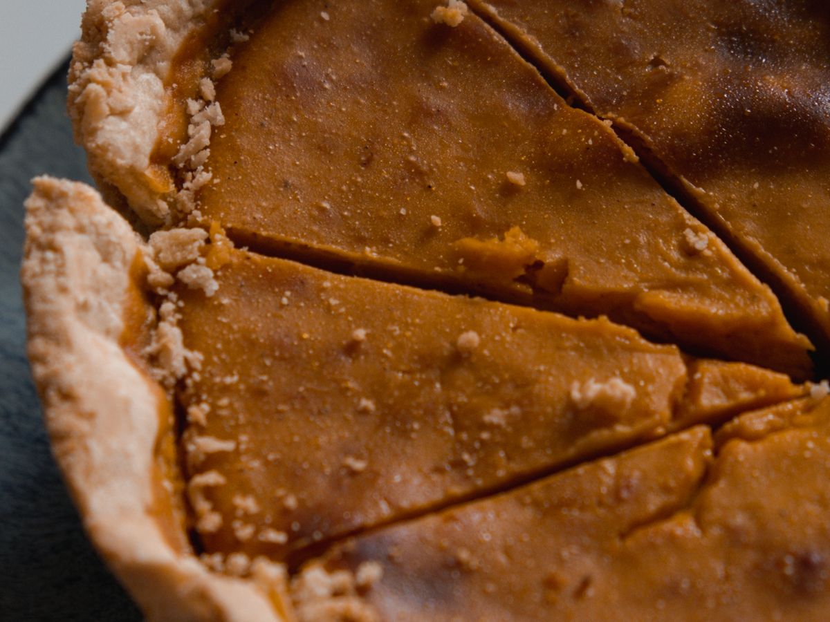A pumpkin pie cut into slices, close up, with a flaky crust