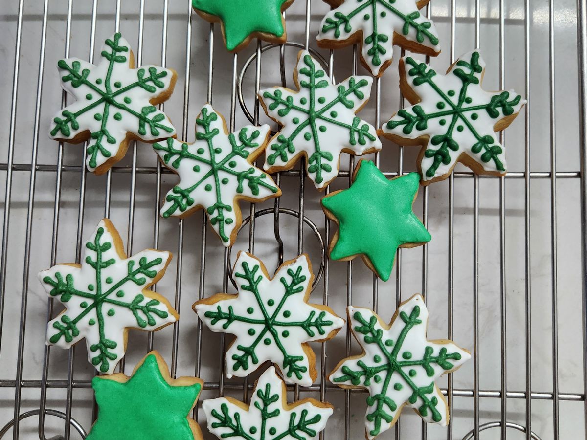 Star and snowflake sugar cookies iced white and green, cooling on a wire rack